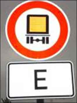 Verkeersbord met een doorkruiste vrachtwagen met gevaarlijke goederen en daaronder een wit bord met de letter E